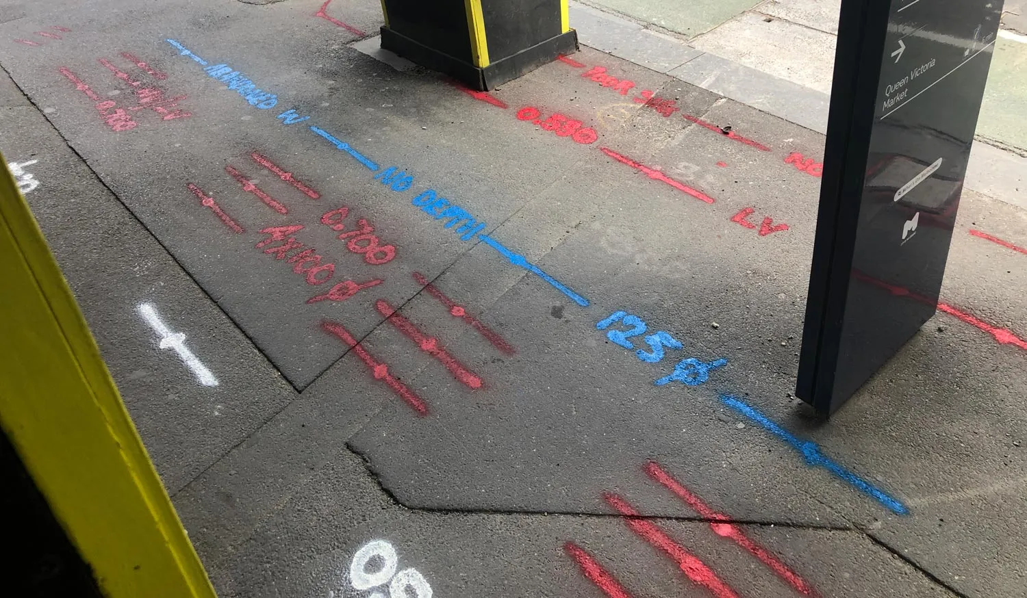 Blue and pink locate marks with depth labels on a footpath