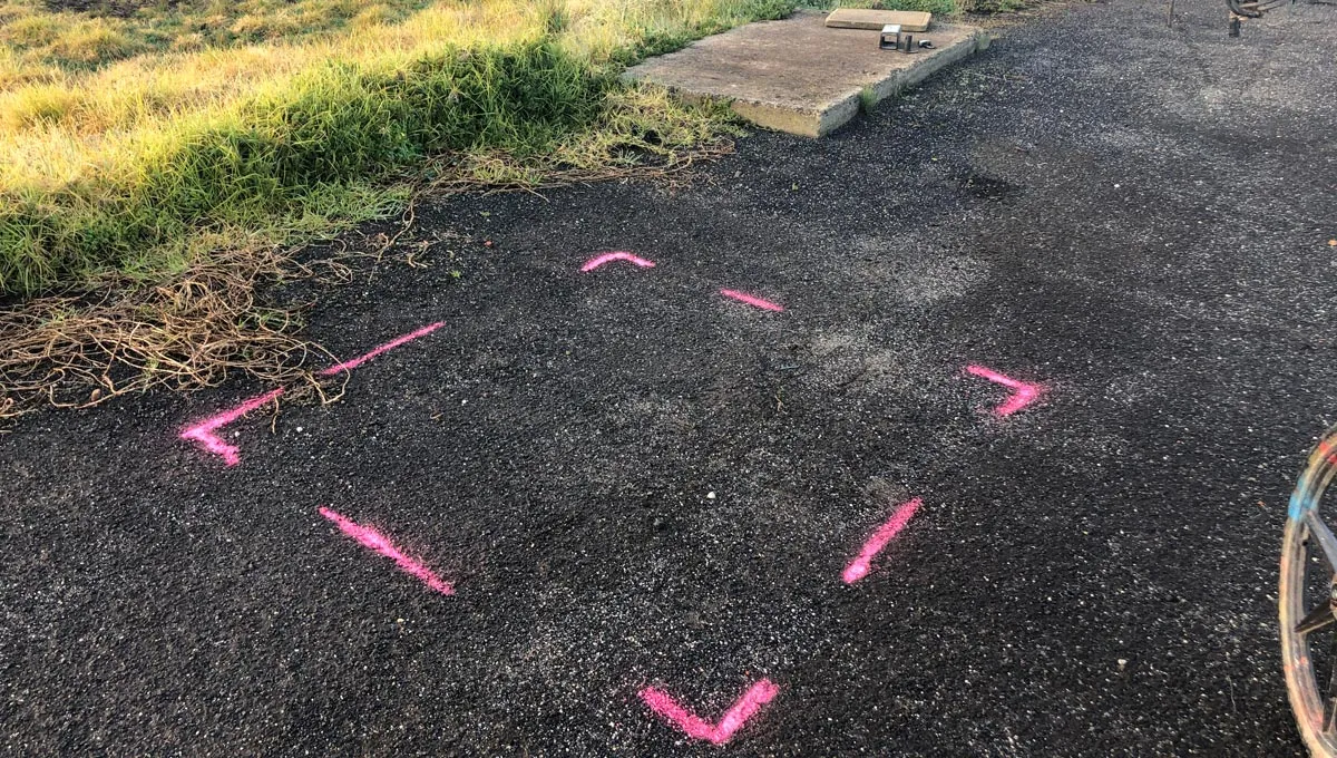 Pink corner marks outlining a scanned crane outrigger pad area on asphalt