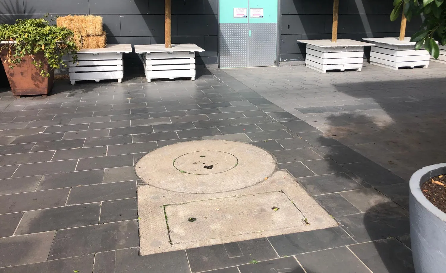 A round tank access lid set into a paved courtyard